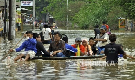 Warga menggunakan jasa perahu kayu untuk menerobos banjir yang merendam di Jalan Raya Banjaran di Kelurahan Andir, Kecamatan Baleendah, Kabupaten Bandung, Rabu (8/3).