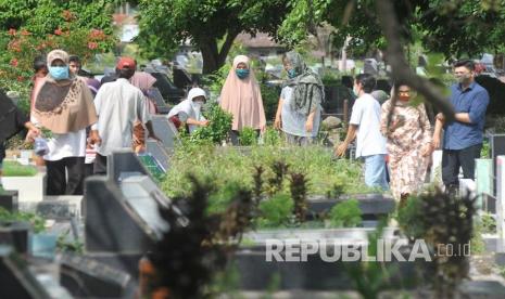 Warga menggunakan masker saat berziarah ke makam keluarganya di Tempat Pemakaman Umum (TPU).