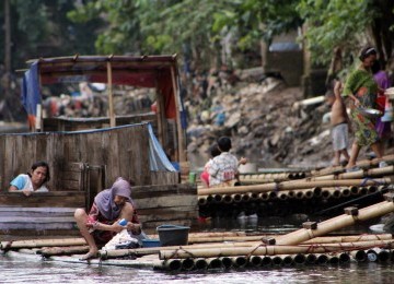 Warga menggunakan MCK darurat di bantaran kali Ciliwung, Bukit Duri, Jakarta, Senin (19/3). (Republika/Adhi Wicaksono)