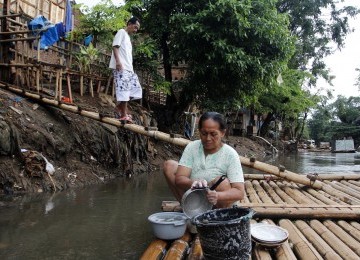 Warga menggunakan MCK darurat di bantaran kali Ciliwung, Bukit Duri, Jakarta, Senin (19/3). (Republika/Adhi Wicaksono)