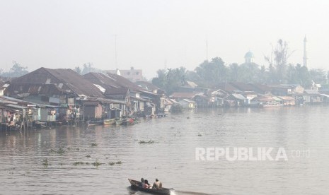 Warga menggunakan perahu bermesin, melintas di Sungai Martapura yang diselimuti kabut asap di Kota Banjarmasin, Kalimantan Selatan, Jumat (8/11/2019). 