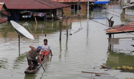 Warga menggunakan perahu melintas di antara rumah yang terendam banjir akibat meluapnya Danau Sentani dampak dari banjir badang Sentani di Kampung Yoboi, Sentani, Jayapura, Papua, Jumat (22/3/2019). 