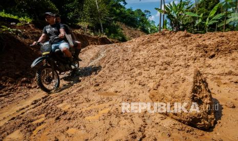 Warga menggunakan roda dua melintas di jalan yang longsor di Desa Banjarsari, Lebak, Banten, Jumat (6/8/2021). Hujan deras yang mengguyur daerah tersebut mengakibatkan jalan antardesa tertimbun longsor pada Rabu (5/8/2021) malam, dikhawatirkan terjadi longsor kembali jika hujan karena tanah yang masih labil