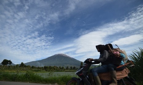 Warga menggunakan sepeda motor dengan latar belakang Gunung Kerinci di Kersik Tuo, Kayu Aro, Kerinci, Jambi, Selasa (30/12).