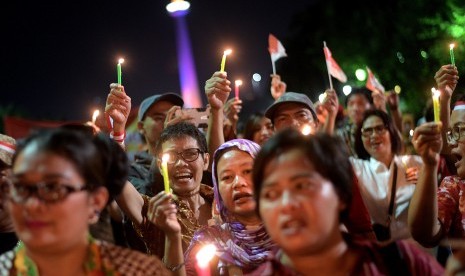 Warga mengikuti aksi damai memperingati Hari Lahir Pancasila di Monas, Jakarta Pusat, Kamis (1/6) malam. Aksi itu untuk mengajak masyarakat bangkit melawan korupsi, radikalisme, intimidasi, intoleransi dan ketidakadilan. 