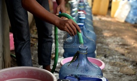 Warga mengisi air bersih ke sebuah galon dari sumur pompa 