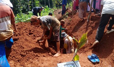 Warga menguburkan pasien dalam pengawasan (PDP) Covid-19 di Desa Cibatuireng, Kecamatan Karangnunggal, Kabupaten Tasikmalaya, Selasa (24/3).