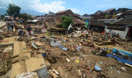 Warga mengumpulkan barang-barang dari puing bangunan rumah yang roboh akibat diterjang banjir bandang aliran Sungai Ciamanuk di Kampung Cimacan, Kecamatan Tarogong, Kabupaten Garut, Jawa Barat, Rabu (21/9). 