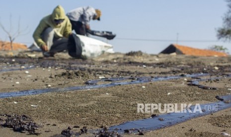 Warga mengumpulkan tumpahan minyak (Oil Spill) yang tercecer di Pesisir Pantai Cemarajaya, Karawang, Jawa Barat, Senin (22/7/2019). 