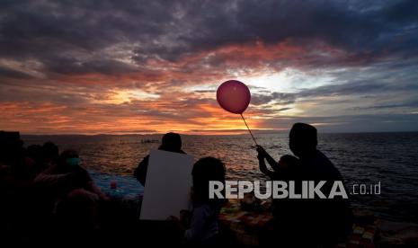 Warga menikmati matahari terbenam (sunset) pada hari terakhir tahun 2020 di Pantai Ampenan, Mataram, NTB, Kamis (31/12/2020). Pantai Ampenan tetap ramai dikunjungi warga menjelang pergantian tahun walaupun pemerintah setempat telah melarang masyarakat melakukan kegiatan yang menimbulkan kerumunan dan merayakan pesta malam pergantian tahun di tengah pandemi COVID-19. 