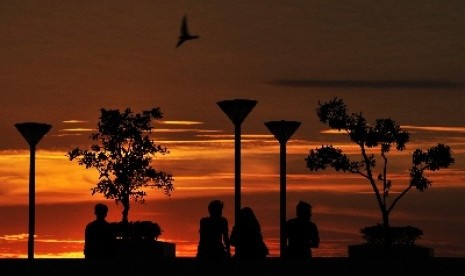 Warga menikmati suasana terbenamnya matahari (sunset) di Pantai Losari Makassar, Sulawesi Selatan, Senin (22/6).