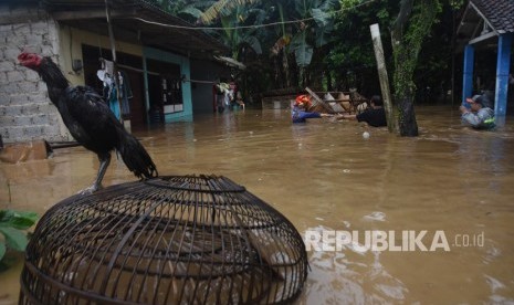 Warga meninggalkan rumahnya yang terendam saat banjir melanda permukiman bantaran Sungai Ciliwung di Jalan Gotong Royong, Kemirimuka, Beji, Depok, Jawa Barat, Senin (5/2).