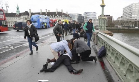 Warga menolong korban terluka di Westminster Bridge, London, Rabu (22/3). Lima orang tewas dan 40 luka dalam serangan di parlemen Inggris.