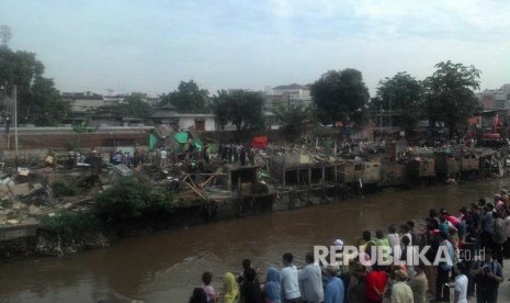 Warga menonton proses penggusuran menggunakan excavator yang menghancurkan bangunan di Bukit Duri, Jakarta Selatan, Rabu (28/9)