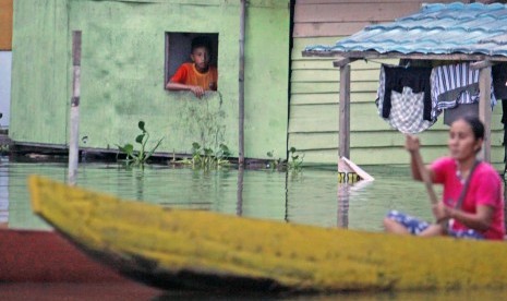 Warga menunggu air surut menyusul banjir yang menggenangi rumah dengan ketinggian 1 meter di Kelurahan Tabumela, Kabupaten Gorontalo, Gorontalo, Minggu (30/10). 