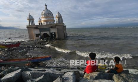 Warga menunggu datangnya waktu berbuka puasa (ngabuburit) di sekitar Masjid Terapung Arkam Babu Rahman yang rusak akibat diterjang tsunami di Pantai Teluk Palu di Palu, Sulawesi Tengah.