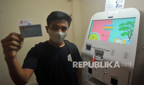 Warga menunjukan KTP elektronik yang baru dicetak menggunakan mesin Anjungan Dukcapil Mandiri (ADM)