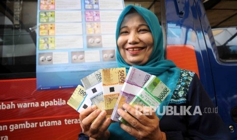  Warga menunjukan uang rupiah baru saat peluncuran uang baru di Blok M Square, Jakarta, Senin (19/12).