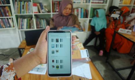 Warga menunjukkan buku elektronik melalui telepon genggam di perpustakaan nasional Taman Baca Masyarakat (TBM) Sakila Kerti, Obyek Wisata Pantai Alam Indah, Tegal, Jawa Tengah, Sabtu (10/9/2022). Perpustakaan nasional berbasis digital (buku elektronik) TBM Sakila Kerti tersebut dibuka untuk warga pesisir dan pedagang obyek wisata itu dengan koleksi sebanyak 200 buah buku untuk memberantas buta aksara sekaligus mendukung pemerintah dalam memberantas anak putus sekolah.