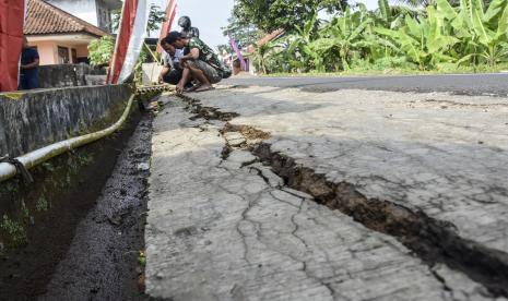 Warga menunjukkan jalan yang retak akibat pergerakan tanah. Ilustrasi.