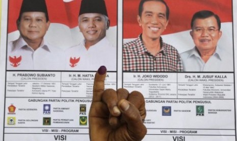 Warga menunjukkan jarinya seusai memberikan hak pilihnya pada pemilihan presiden 2014 