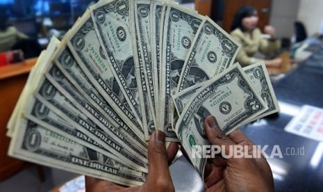 Warga menunjukkan pecahan uang dolar Amerika yang ditukarkan di salah satu gerai penukaran mata uang asing di Jakarta, Rabu (14/3).