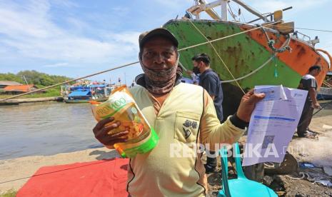 Warga menunjukkan sertifikat vaksin COVID-19 dan minyak goreng kemasan usai mengikuti vaksinasi di Karangsong, Indramayu, Jawa Barat, Senin (14/3/2022). Vaksinasi berhadiah minyak goreng untuk nelayan dan masyarakat pesisir yang digelar Polres Indramayu tersebut guna mendorong percepatan vaksinasi COVID-19. 