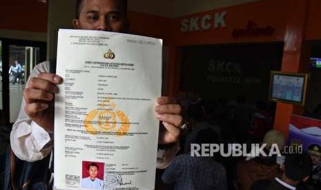 Warga menunjukkan Surat Keterangan Catatan Kepolisian (SKCK) yang telah diproses seusai mengantre di Polresta Depok, Jawa Barat, Selasa (18/9). 