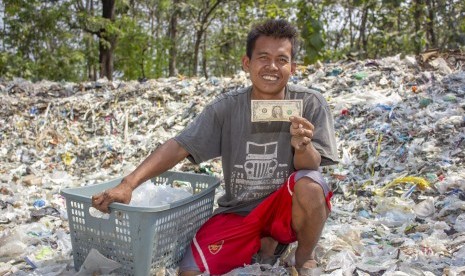 Warga menunjukkan temuan uang dolar Amerika saat memilah sampah plastik di tumpukan sampah impor di Desa Tamansari, Karawang, Jawa Barat, Senin (1/7/2019).