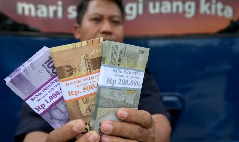 Warga menunjukkan uang pecahan yang ditukarkan dari mobil kas keliling Bank Indonesia di Lapangan IRTI, Monas, Jakarta, Senin (5/6).