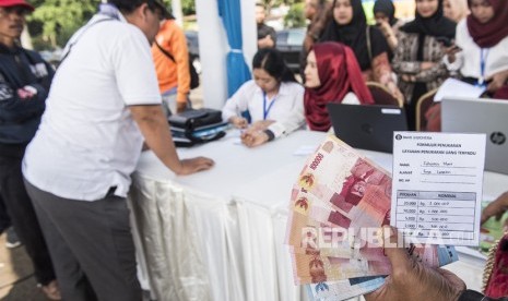 ilustrasi. Warga menunjukkan uang sebelum ditukarkan di loket mobil kas keliling saat pembukaan layanan penukaran uang di Bandung, Jawa Barat, Senin (21/5). 