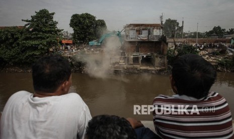 Warga menyaksikan alat berat yang menghancurkan sebuah rumah saat penggusuran di pemukiman proyek normalisasi Sungai Ciliwung, Bukit Duri, Jakarta, Rabu (28/9). 