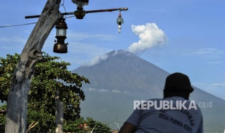 Warga menyaksikan asap putih yang terhembus dari kawah Gunung Agung terlihat dari Amed, Karangasem, Bali, Kamis (7/12). 