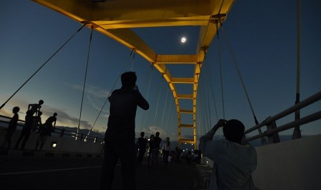 Warga menyaksikan fase puncak Gerhana Matahari Total (GMT) yang dilihat dari Jembatan Teluk Palu, Sulawesi Tengah, Rabu (9/3).