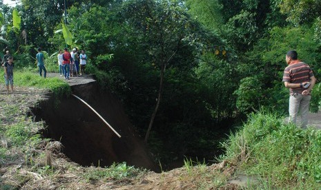 Warga menyaksikan jalan yang putus akibat longsor di Jalan Samsi, Kelurahan Cisarua, Kecamatan Cikole, Sukabumi, Jawa Barat, Jumat (11/12).