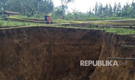 Warga menyaksikan lubang raksasa di area persawahan di Desa Sukamaju, Kadudampit, Kabupaten Sukabumi, Jawa Barat, Ahad (28/4/2019). 