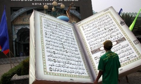 Warga menyaksikan miniatur Alquran raksasa yang di pajang di depan Masjid Raya Al-A'zhom Kota Tangerang, Banten.