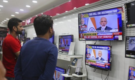 Warga menyaksikan pidato Perdana Menteri India Narendra Modi mengenai pencabuta status otonomi Kashmir melalui televisi di Jammu, India, Kamis (8/8).