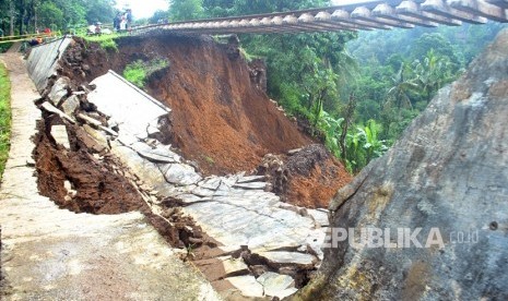 Warga menyaksikan proses evakuasi korban longsor di dekat rel KRD Bogor-Sukabumi sepanjang 40 meter yang menggantung akibat pondasi longsor di Desa Warung Menteng, Kecamatan Cijeruk, Kabupaten Bogor, Jawa Barat, Selasa (6/2).