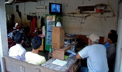  Warga menyaksikan televisi yang menyiarkan hasil rekapitulasi oleh KPU di sebuah tempat cuci motor Jalan Jati Murni, Jakarta Selatan, Selasa (22/7). Warga antusias menunggu hasil rekapitulasi KPU terkait calon presiden dan calon wakil presiden.