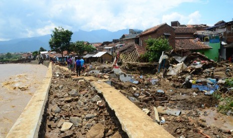 Warga menyaksikkan sisa puing bangunan rumah yang roboh akibat diterjang banjir bandang aliran Sungai Ciamanuk di Kampung Cimacan, Kecamatan Tarogong, Kabupaten Garut, Jawa Barat, Rabu (21/9). 