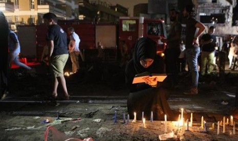 Warga menyalakan lilin di lokasi pengeboman bunuh diri di Karada, sebuah tempat perbelanjaan sibuk di Baghdad, Ahad, 3 Juli 2016. Saat itu, banyak warga sedang berbelanja untuk kebutuhan Idul Fitri.