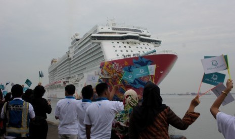 Warga menyambut kedatangan kapal pesiar Genting Dream yang akan sandar di Dermaga Jamrud Utara, Pelabuhan Tanjung Perak Surabaya, Jawa Timur, Selasa (12/12). Kapal pesiar tersebut mengangkut sekitar 2.561 wisatawan asing yang berkunjung ke sejumlah tempat wisata di Kota Surabaya.