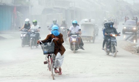  Warga menyeberangi jalan yang tertutup abu vulkanik di kawasan Kutoarjo, Purworejo, Jawa Tengah, Sabtu (15/2). (Republika/Adhi Wicaksono)