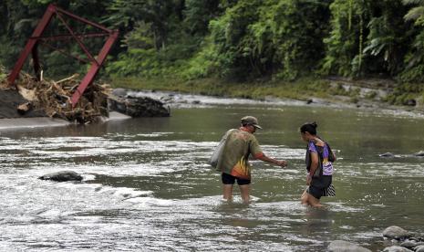 Warga menyeberangi sungai saat pulang menuju rumah di lingkungan Dauh Tukad, Desa Nusamara, Yehembang Kangin, Jembrana, Bali, Senin (24/10/2022). Sebanyak 21 kepala keluarga terisolir sejak November 2021 akibat jembatan gantung putus diterjang luapan air sungai. 