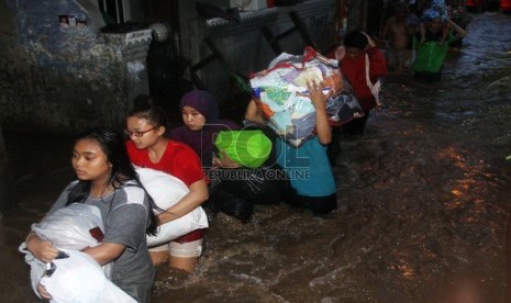   Warga menyelamatkan barang-barangnya ketika melintasi banjir yang merendam kawasan Kampung Pulo, Jakarta, Ahad (12/1).   (Republika/Yasin Habibi)