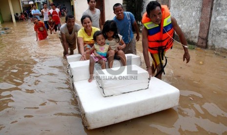   Warga menyelamatkan keluarga mereka saat banjir merendam rumah mereka di Kampung Poncol,Kelurahan Bukit Duri, Kecamatan Tebet,Jakarta Selatan,Senin (24/12).  (Republika/Prayogi)