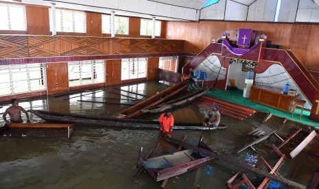 Warga merapikan kursi gereja yang terendam banjir akibat meluapnya Danau Sentani dampak dari banjir bandang Sentani di Kampung Yoboi, Danau Sentani, Sentani, Jaya Pura, Papua, Jumat (22/3/2019).