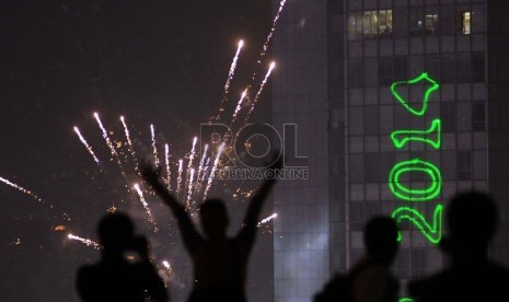   Warga merayakan pergantian tahun baru pada atap gedung saat pergantian tahun di Bundaran HI, Jakarta, Rabu (1/1) dini hari.   (Republika/Tahta Aidilla)