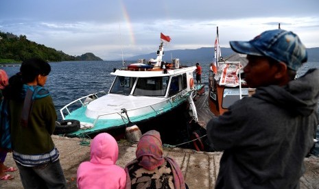 Warga mnyaksikan kapal Basarnas berlabuh usai operasi SAR korban tenggelamnya KM Sinar Bangun di dermaga Tigaras, Danau Toba, Simalungun, Sumatera Utara, Minggu (1/7). 